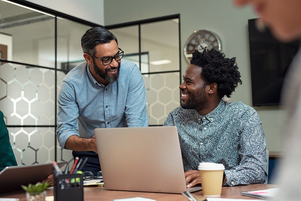 Portrait of two casual business partners sitting at table together and working.