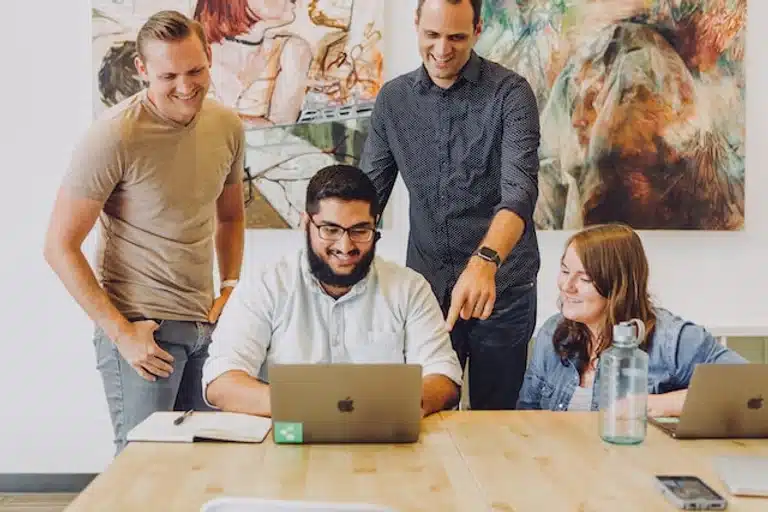 Team in an office working together, pointing to a laptop